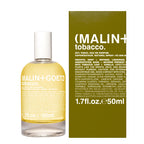 A bottle of Malin + Goetz Tobacco Eau de Parfum next to its olive green outer box, featuring the brand name 'MALIN + TOBACCO' in white text on the packaging.